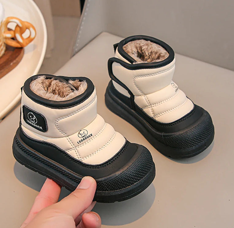 Pair of white and black children's snow boots on a light surface.