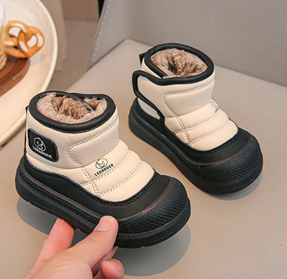 Pair of white and black children's snow boots on a light surface.